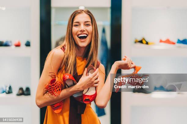 attractive woman in the shoe store holding a pile of new shoes - fashion shopping stockfoto's en -beelden