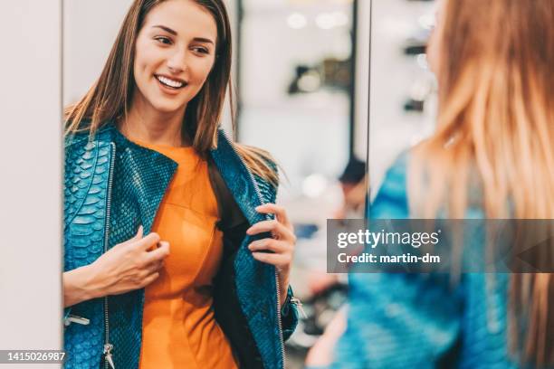 junge frau in der shopping mall genießen eine lederjacke - kleidung anprobe stock-fotos und bilder