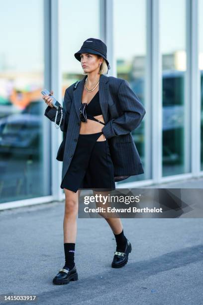 Guest wears a black bob from Jacquemus, gold earrings, a gold and white pearls with silver chain double necklace, a black V-neck laces waist cropped...