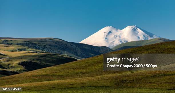 scenic view of snowcapped mountains against clear blue sky,mt elbrus,russia - montagnes du caucase photos et images de collection