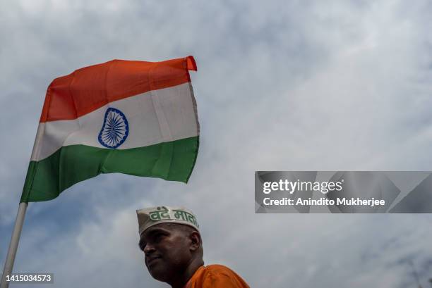 Man taking part in India's Independence day celebrations, stands besides a India flag on August 15, 2022 in New Delhi, India. India celebrates its...