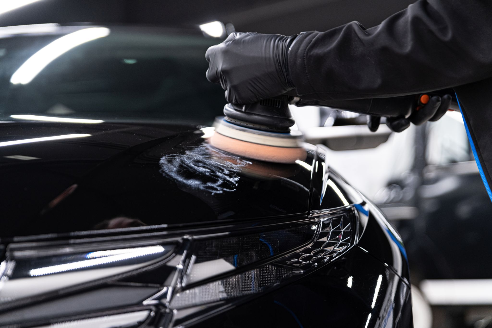 Man worker of car detailing studio removing scratches on car varnish Man worker of car detailing studio removing scratches on car varnish
