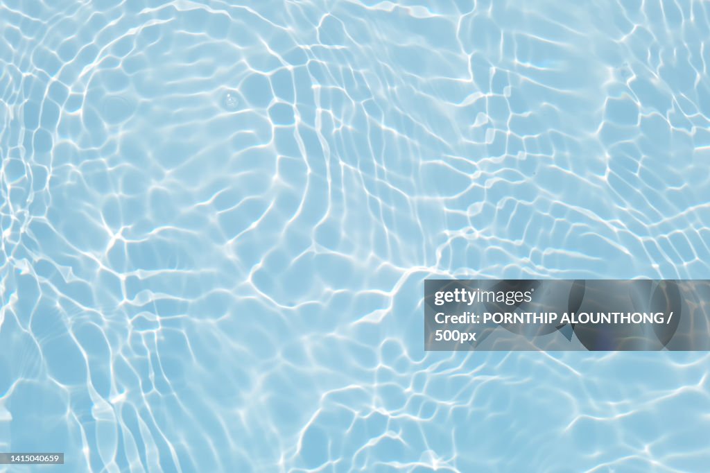 Defocus blurred transparent blue colored clear calm water surface texture with splashes and bubble