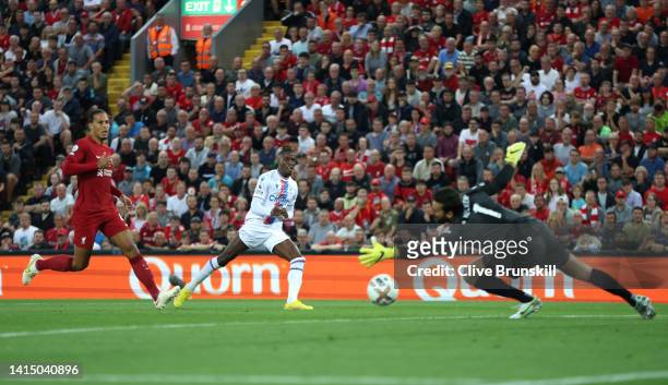 Wilfried Zaha of Crystal Palace scores their team's first goal past Alisson Becker of Liverpool during the Premier League match between Liverpool FC...