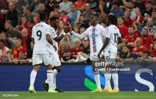 Wilfried Zaha of Crystal Palace celebrates with teammates after scoring their team's first goal during the Premier League match between Liverpool FC...