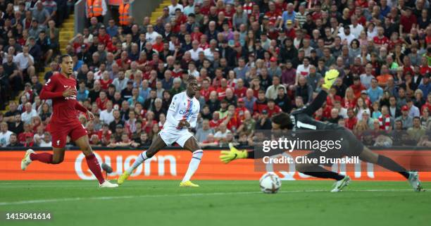 Wilfried Zaha of Crystal Palace scores their team's first goal past Alisson Becker of Liverpool during the Premier League match between Liverpool FC...