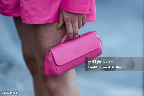 Guest wears a neon pink oversized shirt from Norr, matching neon pink shorts, a pink shiny leather east-west handbag, outside Saks Potts during...