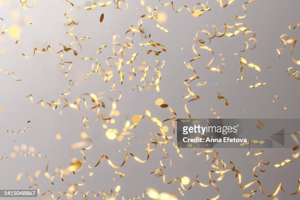 many falling golden serpentine confetti on gray background. festive christmas backdrop. three dimensional illustration - tinsel - fotografias e filmes do acervo