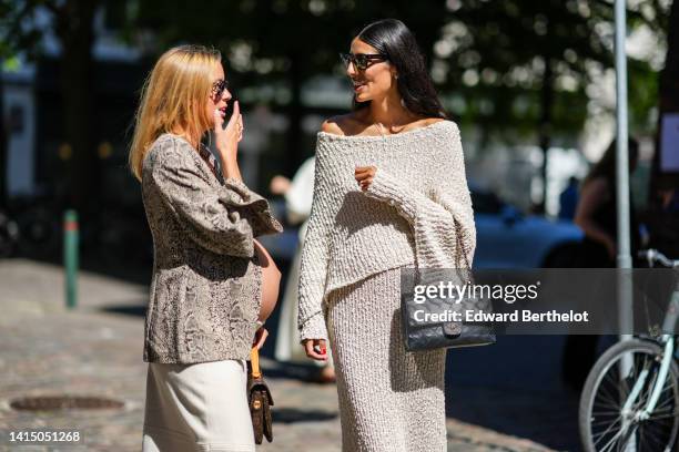 Guest wears black sunglasses, a beige and black snake print pattern jacket with a white embroidered large flower, a beige slit / split midi skirt, a...