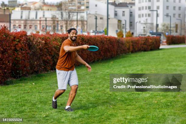 young african athlete is playing with frisbee in public park. - flying disc stock pictures, royalty-free photos & images