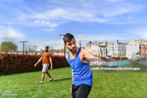 young athlete is playing with frisbee in public park. - throwing frisbee stock pictures, royalty-free photos & images