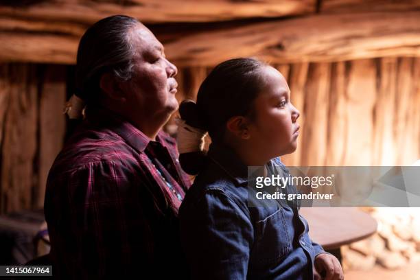 porträt eines vaters und eines sohnes, die sitzen und ihre geflochtenen haare zeigen - handsome native american men stock-fotos und bilder