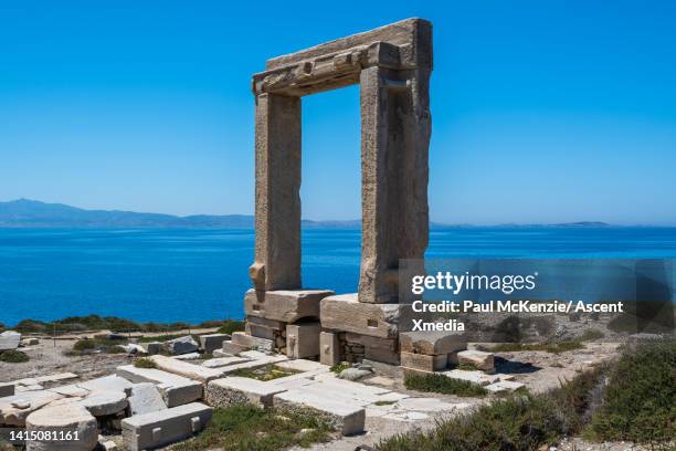 temple opening stands on hillside above sea - templo de apolo naxos imagens e fotografias de stock