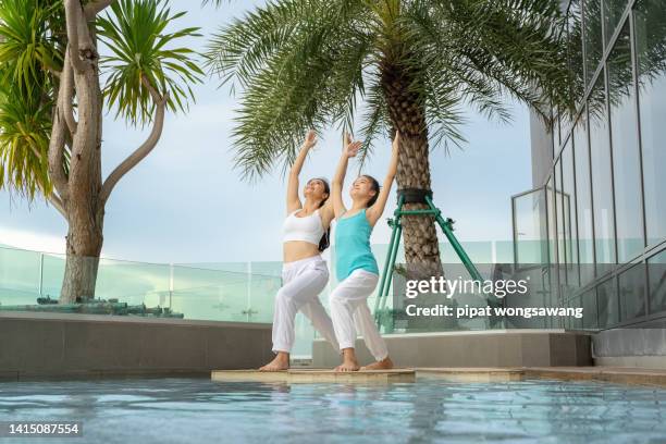 yoga teacher teaches a girl to do yoga by the pool of a skyscraper condominium.relaxation concept, residential house, real estate - real people family portraits stockfoto's en -beelden