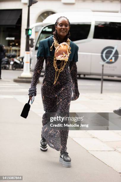 Michelle Elie wears a gold chain animal teeth necklace accessory, print dress, chunky back and white striped platform Comme des Garcons x Nike Cortez...