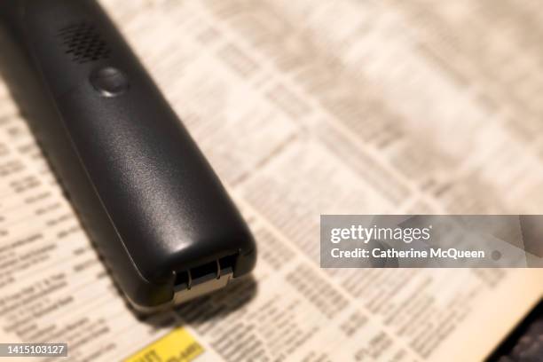 traditional cordless telephone with white pages in phone directory in background (turned over) - telefonbuch stock-fotos und bilder