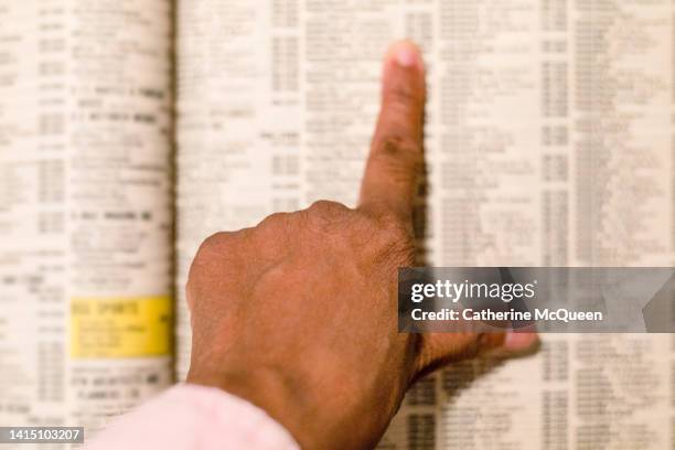 black woman searches for telephone number in traditional paper telephone book - telefonkatalog bildbanksfoton och bilder