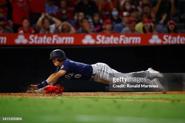 Sam Haggerty of the Seattle Mariners slides safely into home plate against the Los Angeles Angels in the ninth inning at Angel Stadium of Anaheim on...