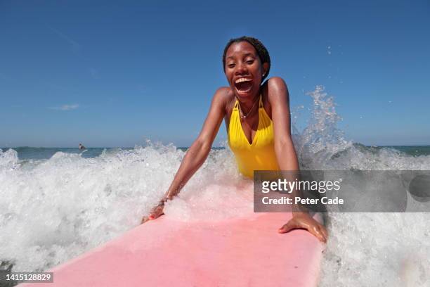 african woman lying on surfboard - polzeath photos et images de collection