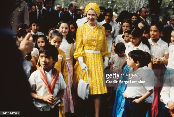 Queen Elizabeth II with a group of local children during her state visit to Mexico, February-March 1975.