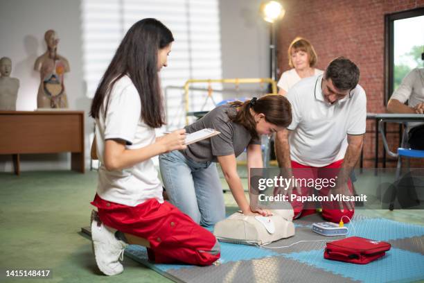 she is performing cpr from a dummy with close guidance from her teacher and assistant teacher. - school close up stock-fotos und bilder