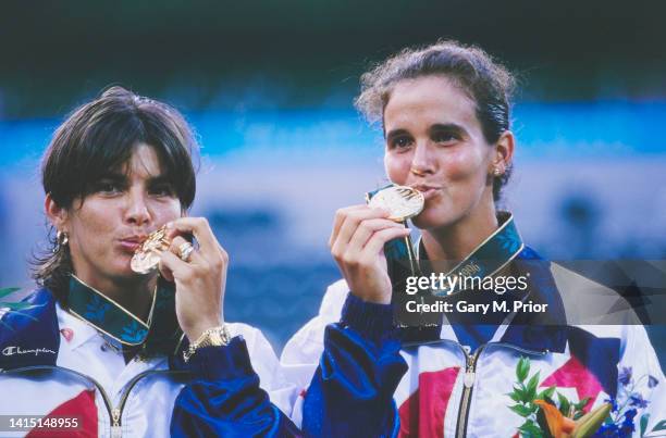 Gigi Fernández and Mary Joe Fernández of the United States celebrate on the winners podium by kissing their the gold medal after defeating silver...