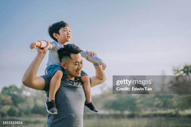 asian chinese father carrying his son on shoulder at public park enjoying bonding time together  during weekend leisure time - malaysia father and son stockfoto's en -beelden