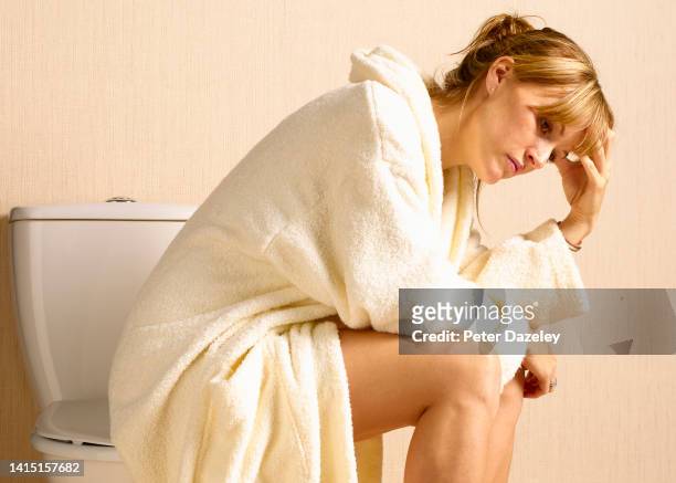depressed woman sitting on toilet - woman hemorrhoids stock pictures, royalty-free photos & images