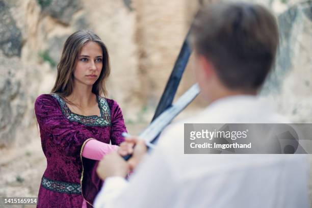 teenage princess practicing swordplay with a teenage knight - duelleren stockfoto's en -beelden