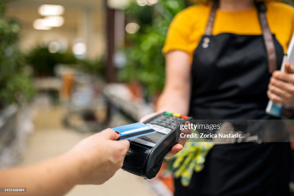 Travailleurs de serre vendant des fleurs potées, achat par carte de crédit