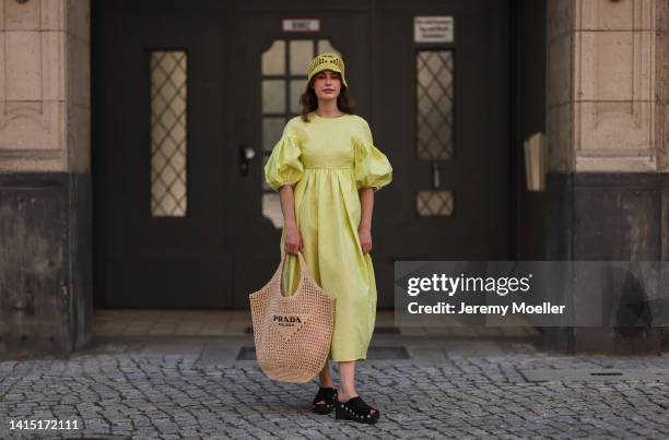 Lea Naumann seen wearing Cecilie Bahnsen neon yellow green long dress with puffer sleeves, Prada neon yellow Raphia bast bucket hat, Prada logo beige...