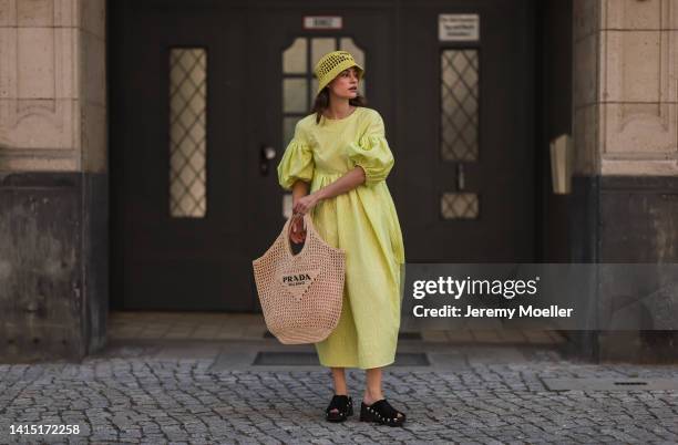 Lea Naumann seen wearing Cecilie Bahnsen neon yellow green long dress with puffer sleeves, Prada neon yellow Raphia bast bucket hat, Prada logo beige...