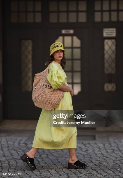 Lea Naumann seen wearing Cecilie Bahnsen neon yellow green long dress with puffer sleeves, Prada neon yellow Raphia bast bucket hat, Prada logo beige...