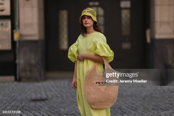 Lea Naumann seen wearing Cecilie Bahnsen neon yellow green long dress with puffer sleeves, Prada neon yellow Raphia bast bucket hat and Prada logo...