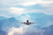 jet flight travel concept stock photo. Airplane fly above amazing blue misty mountain