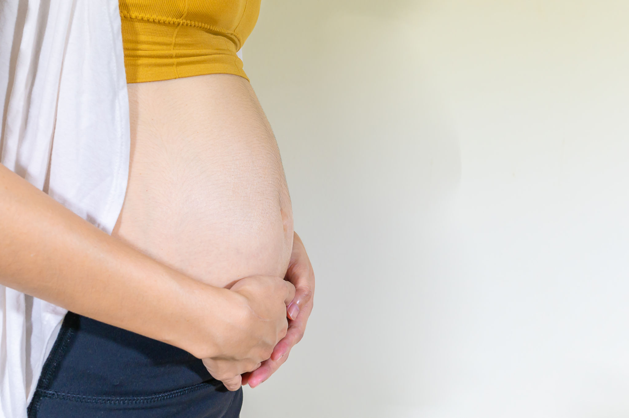 Pregnant woman standing and touching her belly, Second trimester pregnancy, Mother show love feeling, Baby is loading, Copy space, Close up Pregnant woman standing and touching her belly, Second trimester pregnancy, Mother show love feeling, Baby is loading, Copy space, Close up