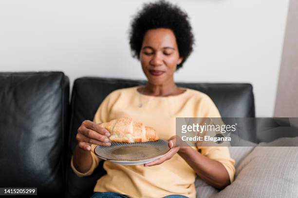 close up of a young woman eating croissants at home - eating croissant stock pictures, royalty-free photos & images