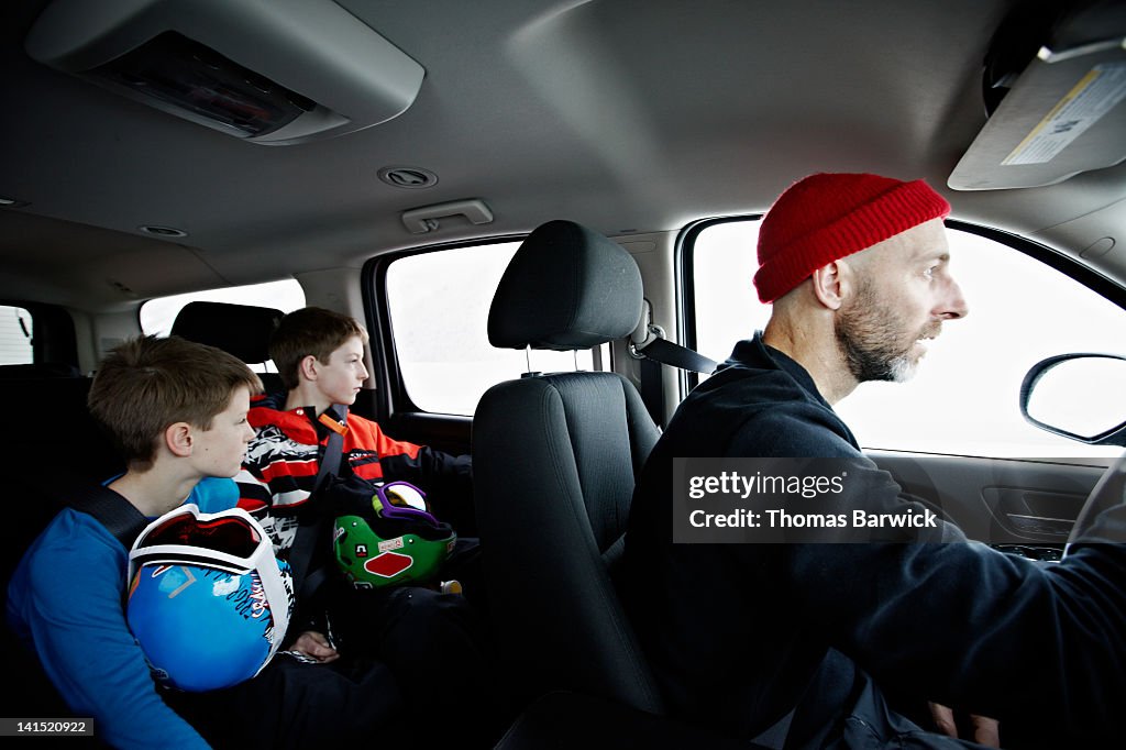 Father and two young sons riding in car