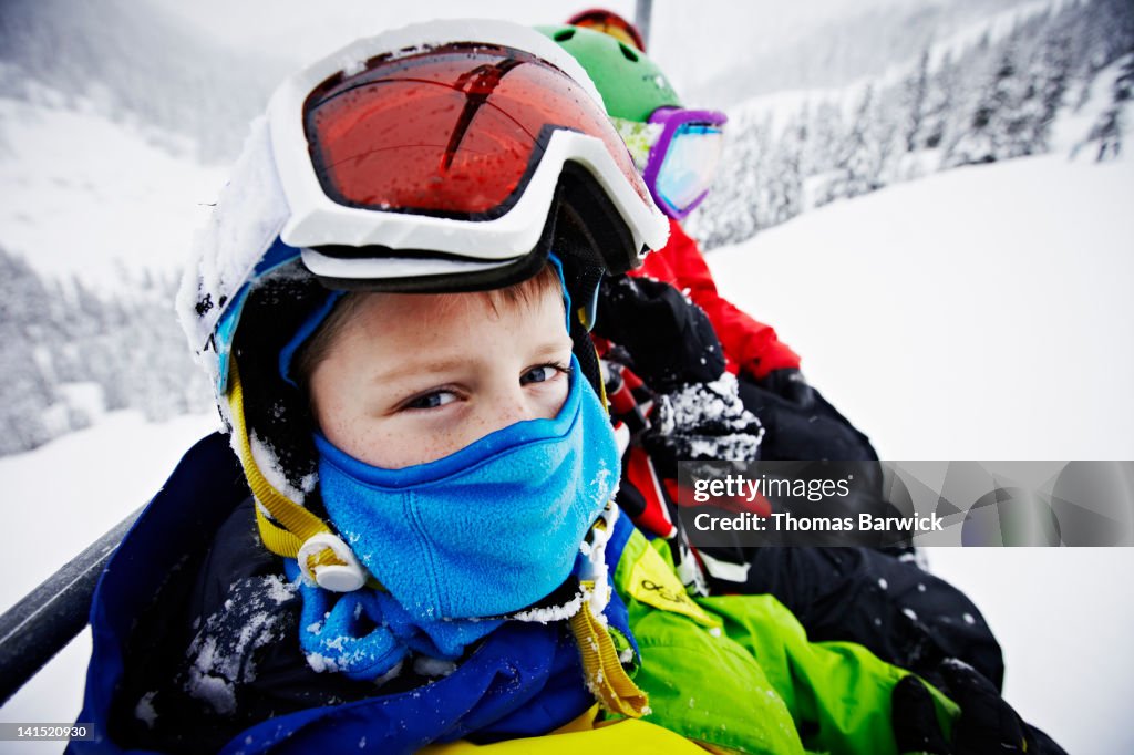 Young boy riding chair lift with dad and brother