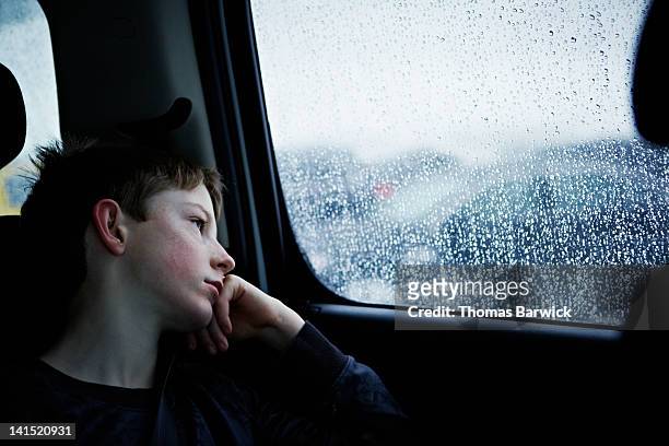 young boy looking out rainy car window - förödmjukelse bildbanksfoton och bilder