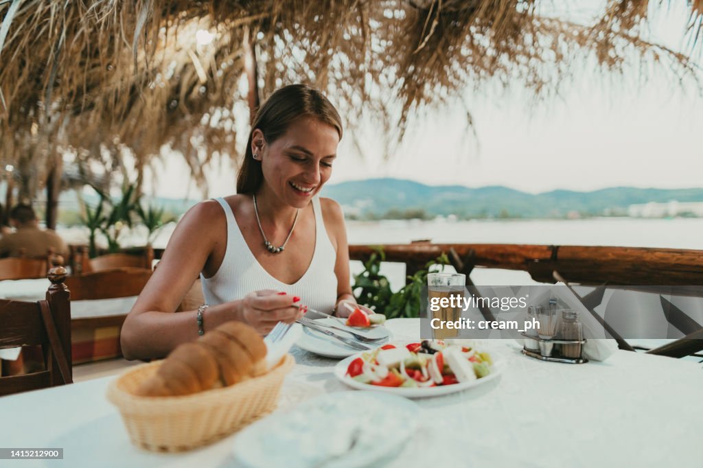 Frau isst griechischen Salat in einem Restaurant am Meer in Griechenland