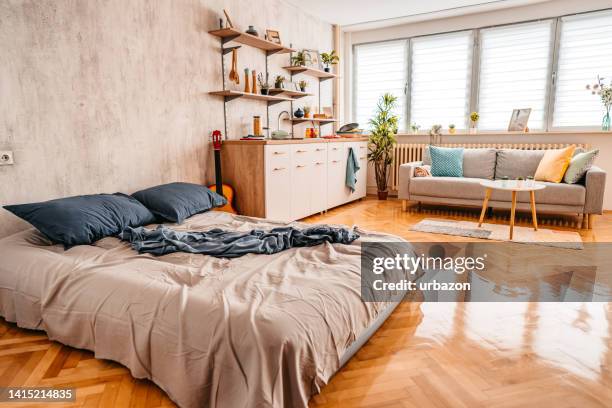 messy bed in studio apartment - studio apartment stock pictures, royalty-free photos & images