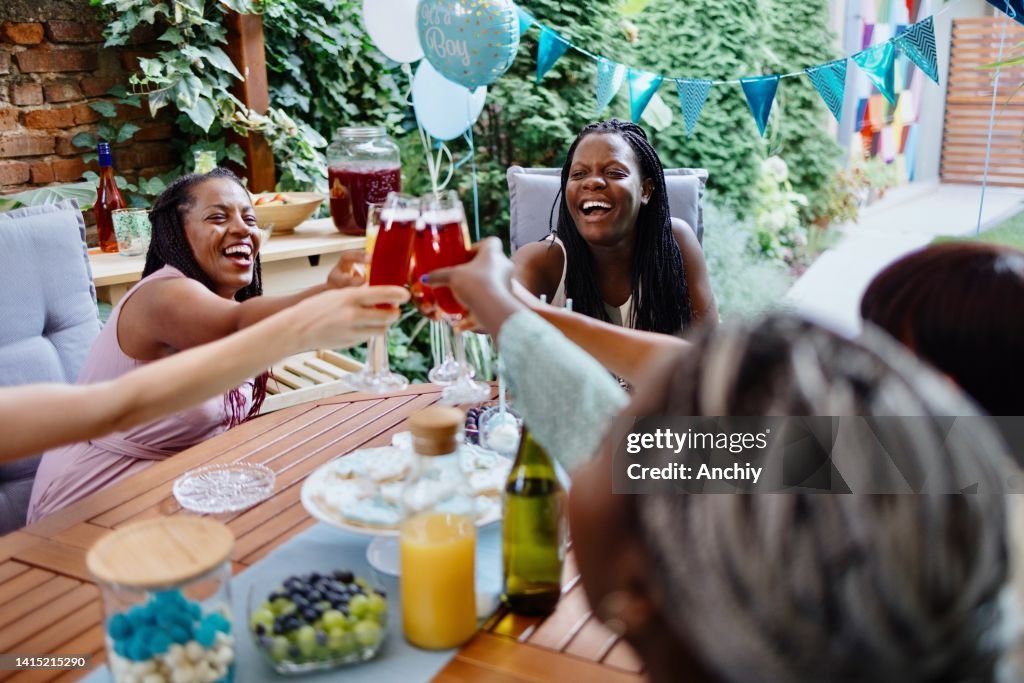 Joven embarazada sonriente celebrando el baby shower con sus mejores amigas.