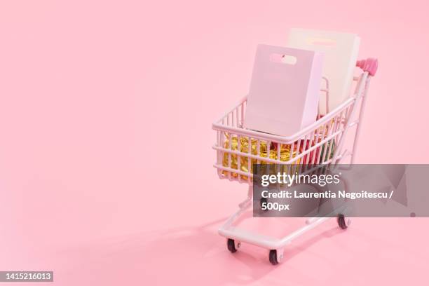 annual sale shopping season concept - mini pink shop cart trolley full of paper bag gift isolated on - shopping trolleys stockfoto's en -beelden