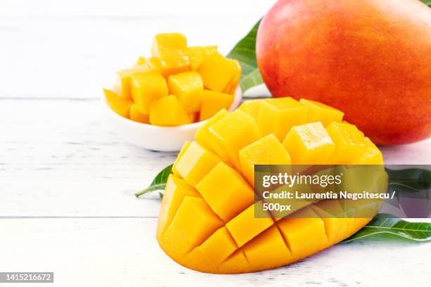 beautiful chopped mango with green leaves on bright white color timber background above top view,f - マンゴー ストックフォトと画像