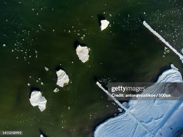 frozen snowy seacoast with ice floating on seawater - real time stock pictures, royalty-free photos & images