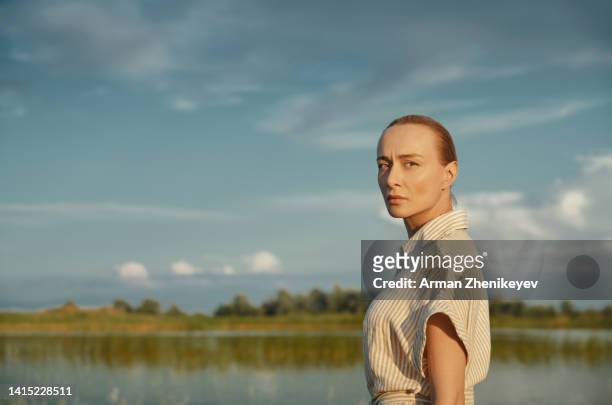portrait of the beautiful woman wearing vintage dress next to the pond. nicely fits for book cover - three quarter length stock pictures, royalty-free photos & images