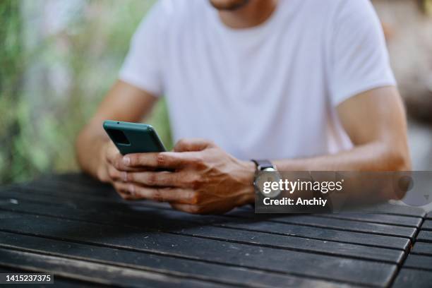 man checking his cell phone at a coffee shop while drinking a cappuccino - phone message stock pictures, royalty-free photos & images