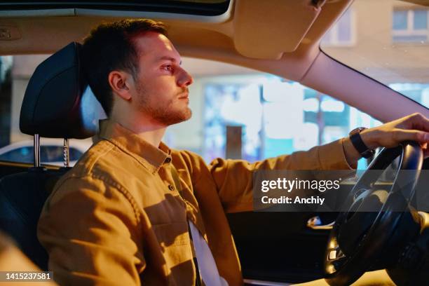 young man driving car at night - management car smartphone stock pictures, royalty-free photos & images
