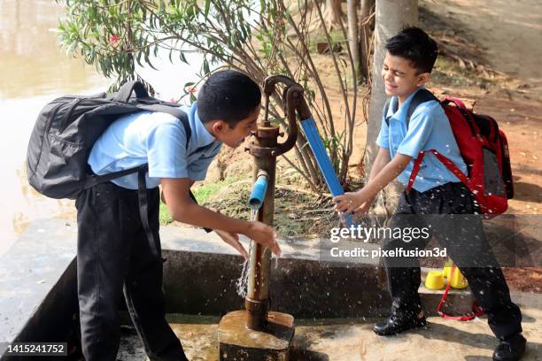 elementary age child filling water bottle during school time on water pump outdoor in nature. - water pump 個照片及圖片檔